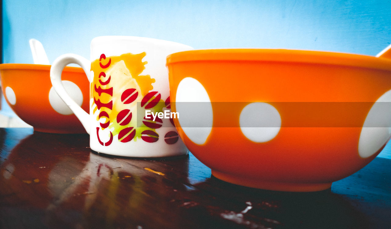 CLOSE-UP OF COFFEE CUP ON TABLE AGAINST ORANGE SKY