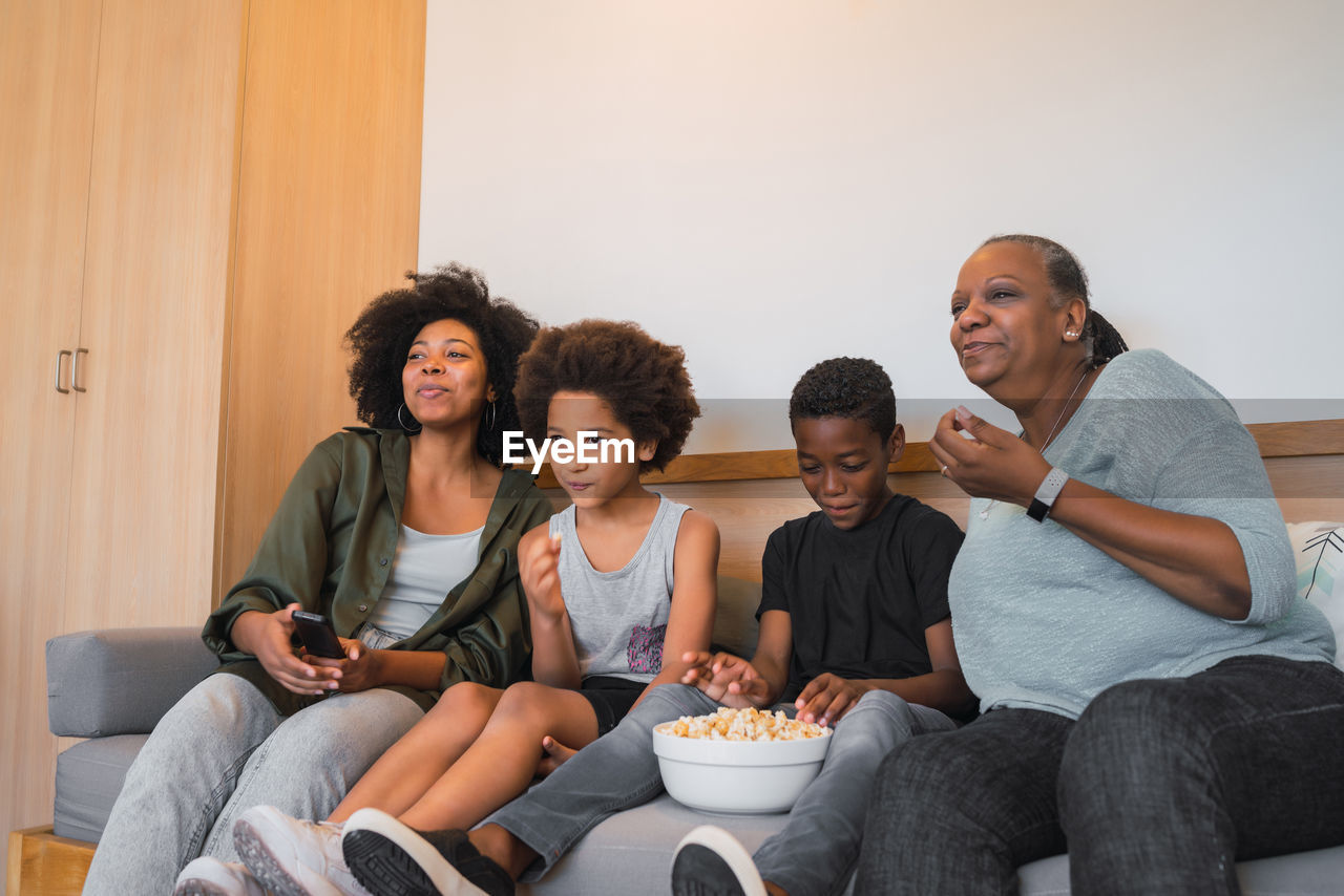 Family watching tv while sitting on sofa at home