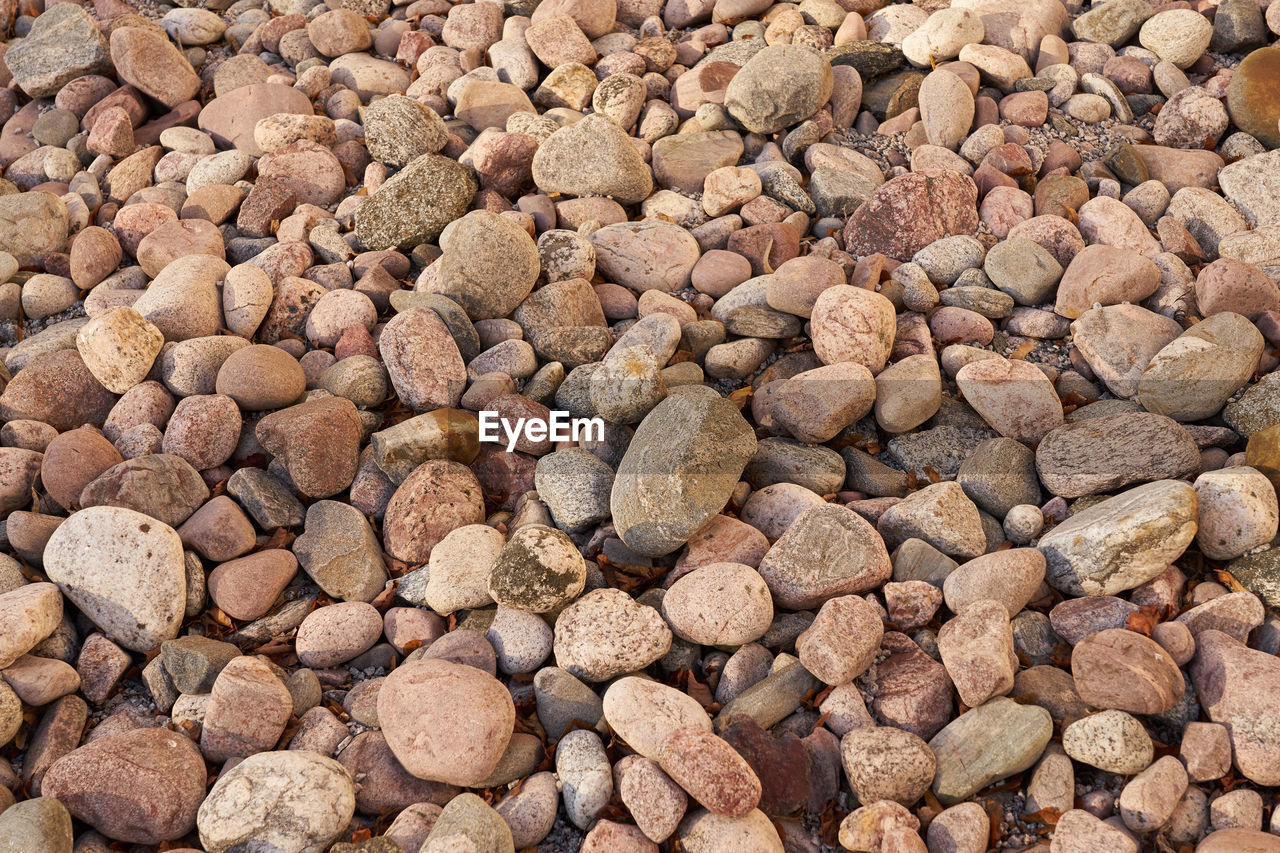 HIGH ANGLE VIEW OF PEBBLES ON BEACH