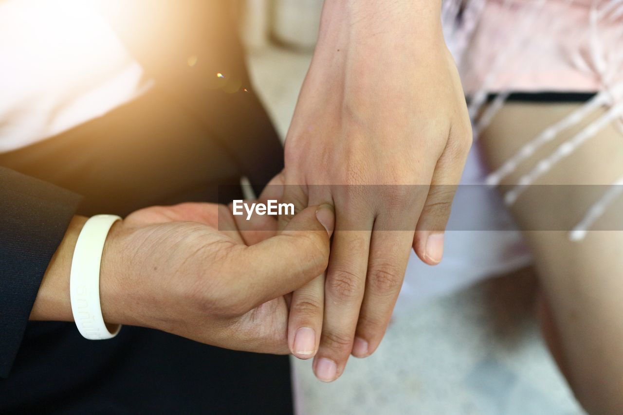 Close-up high angle view of boyfriend holding girlfriend hand