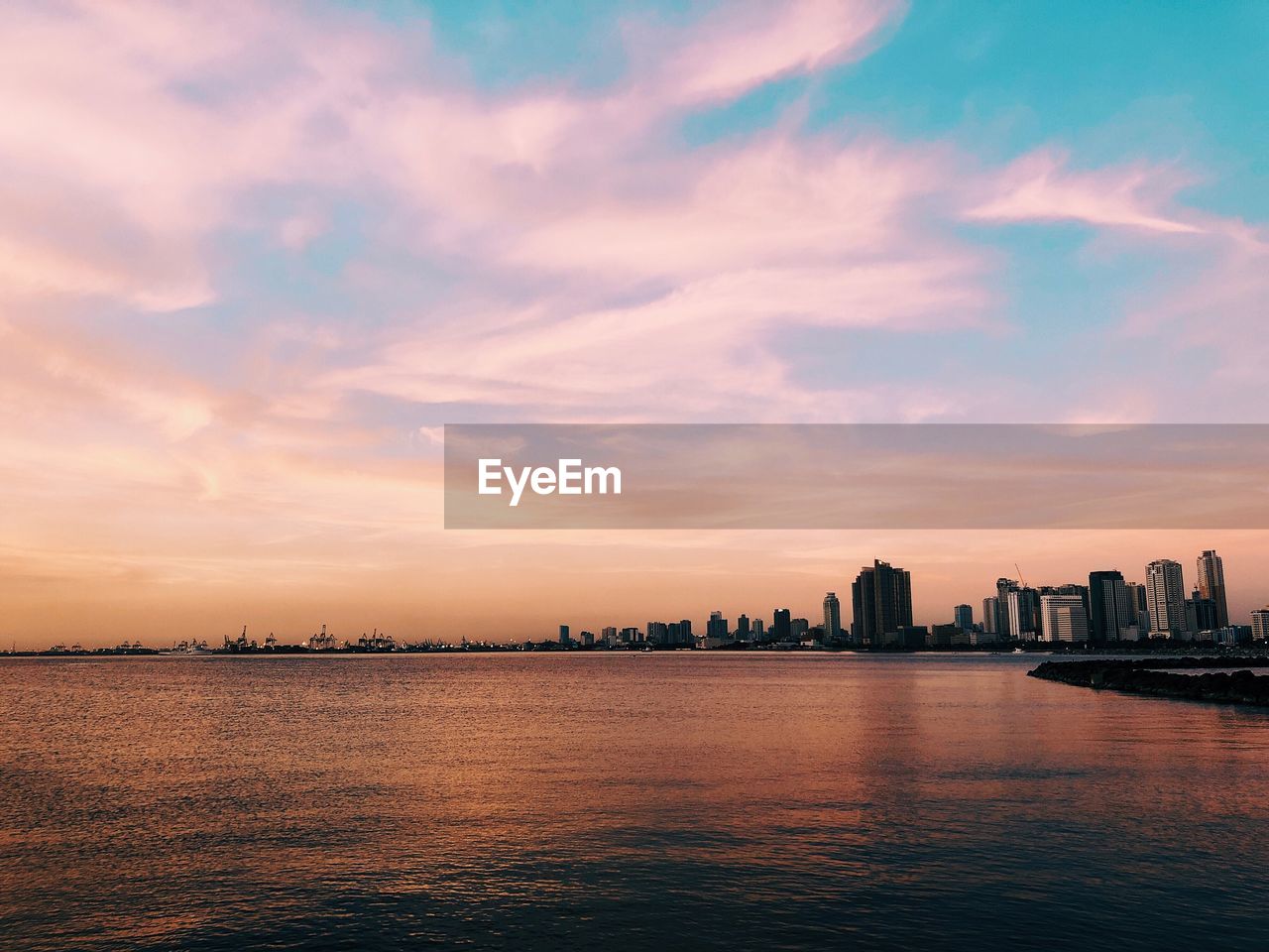 Scenic view of sea and buildings against sky during sunset