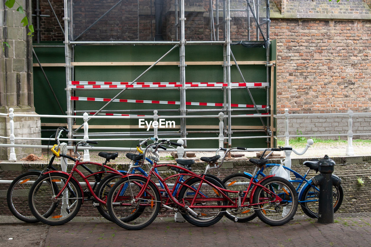 Bicycles and tandems on a wall with a construction site
