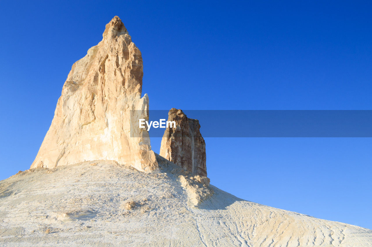 sky, blue, nature, mountain, clear sky, scenics - nature, landscape, rock, beauty in nature, environment, travel destinations, rock formation, no people, formation, land, travel, sunny, non-urban scene, geology, desert, day, tranquility, outdoors, sunlight, tranquil scene, extreme terrain, plateau, mountain range, low angle view, physical geography, terrain, copy space, remote