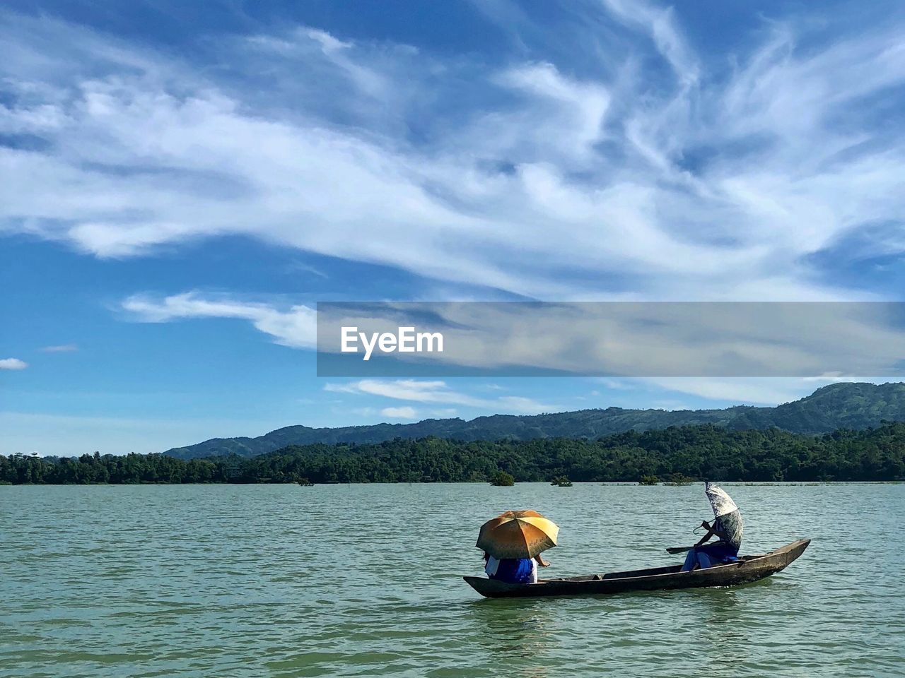 People in boat on lake against sky