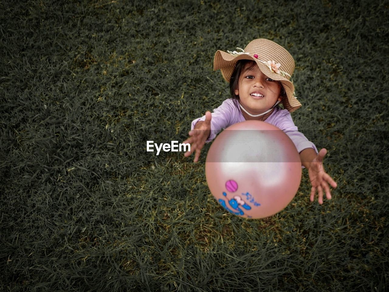 Playing child. pink ball with green grass background. 