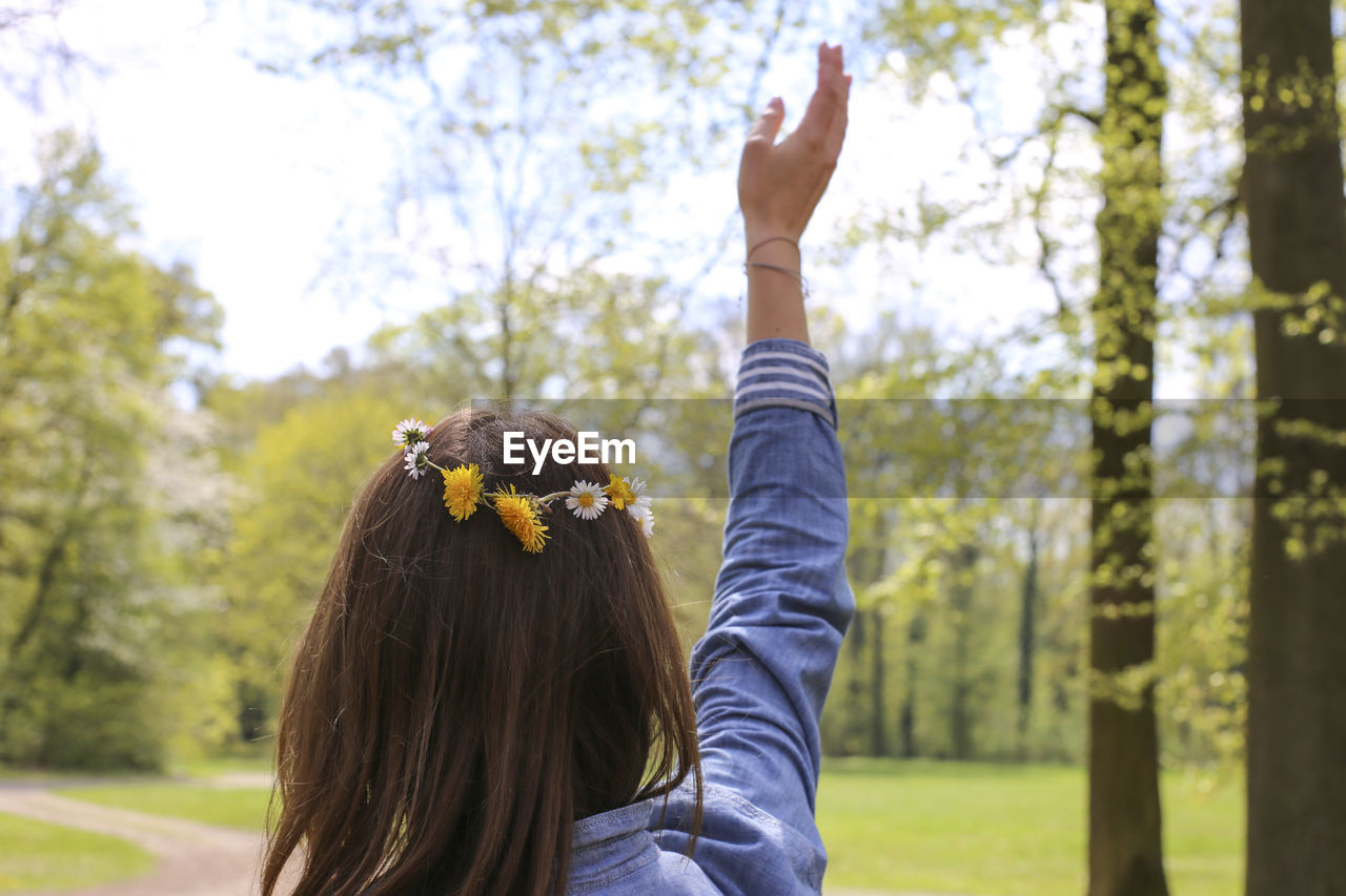 Rear view of woman with arms raised against plants