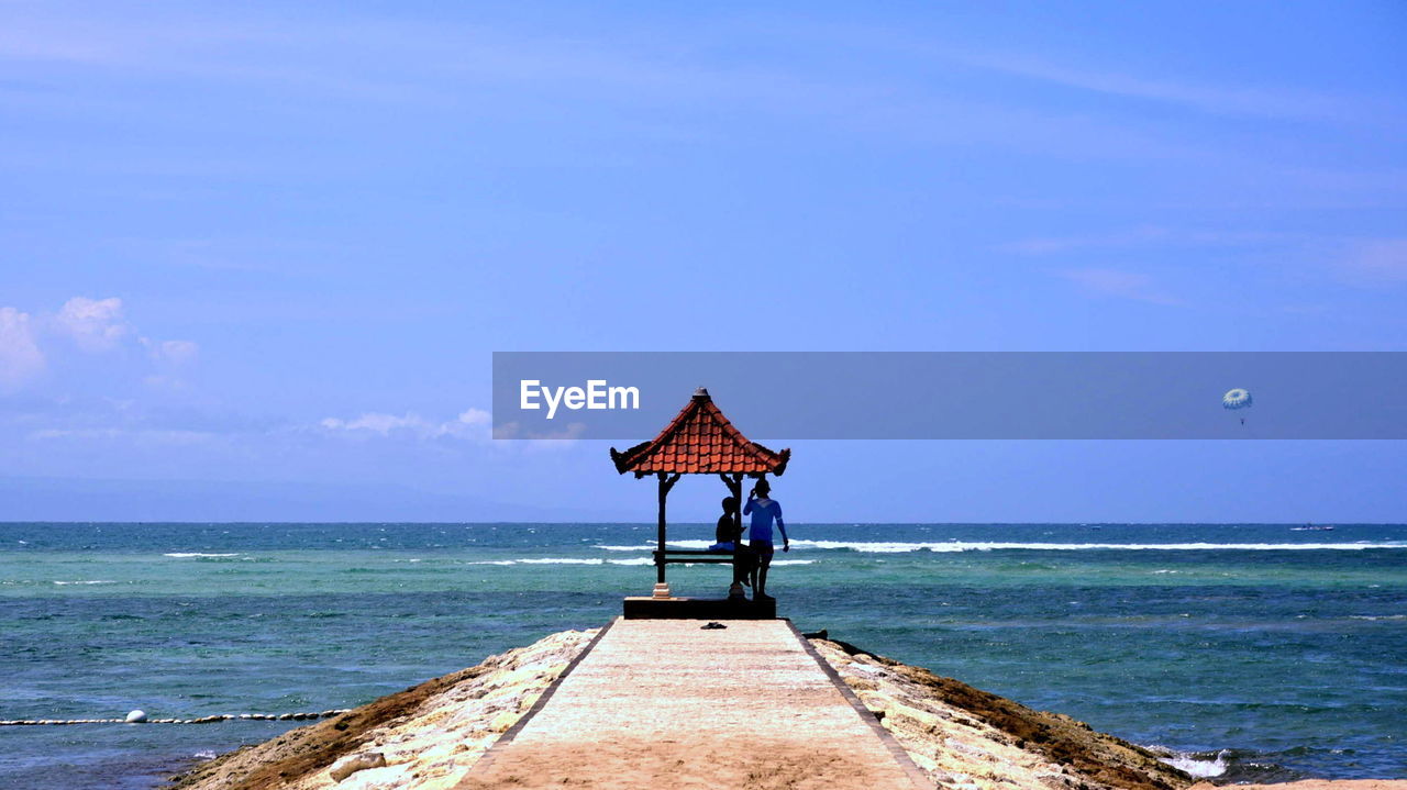 Tourists on jetty against sky