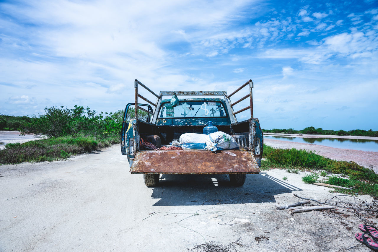 Old pick-up truck on road against sky