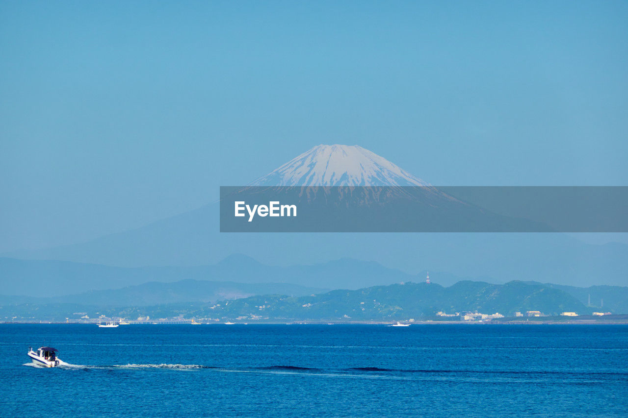 Scenic view of sea and snowcapped mountains against clear sky