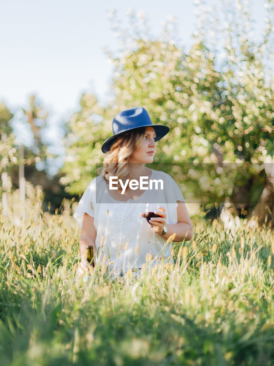 YOUNG WOMAN USING PHONE ON FIELD