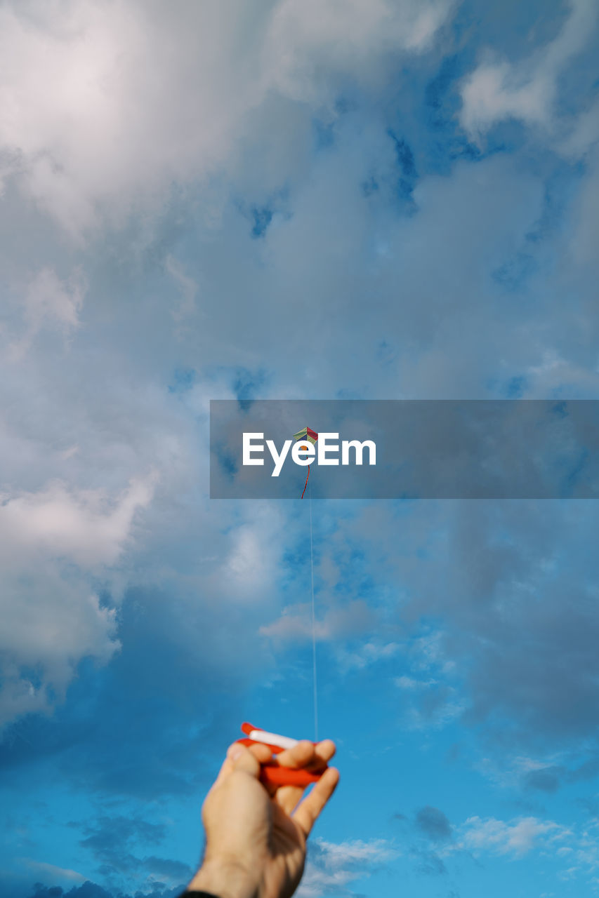 low angle view of woman with arms raised against sky