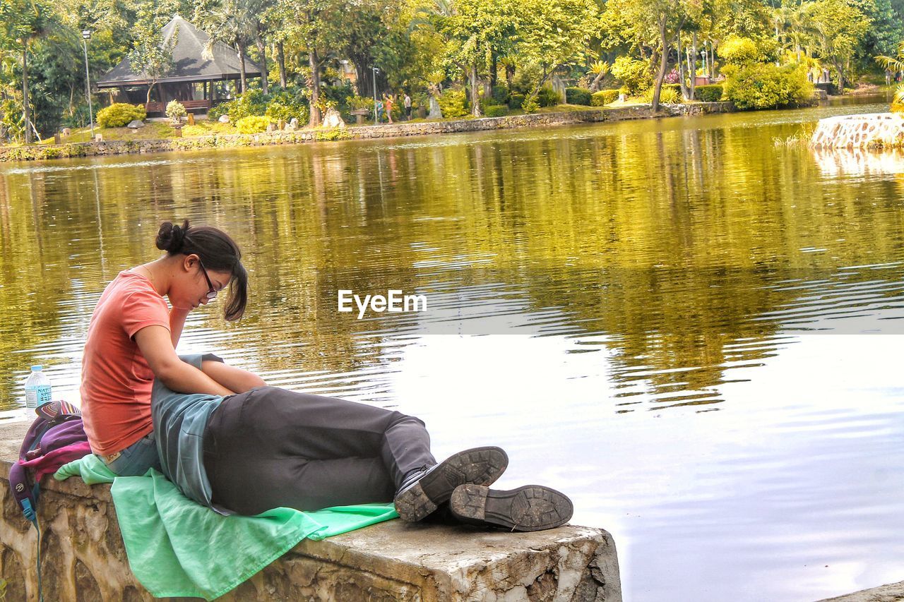 Couple relaxing at lake against trees