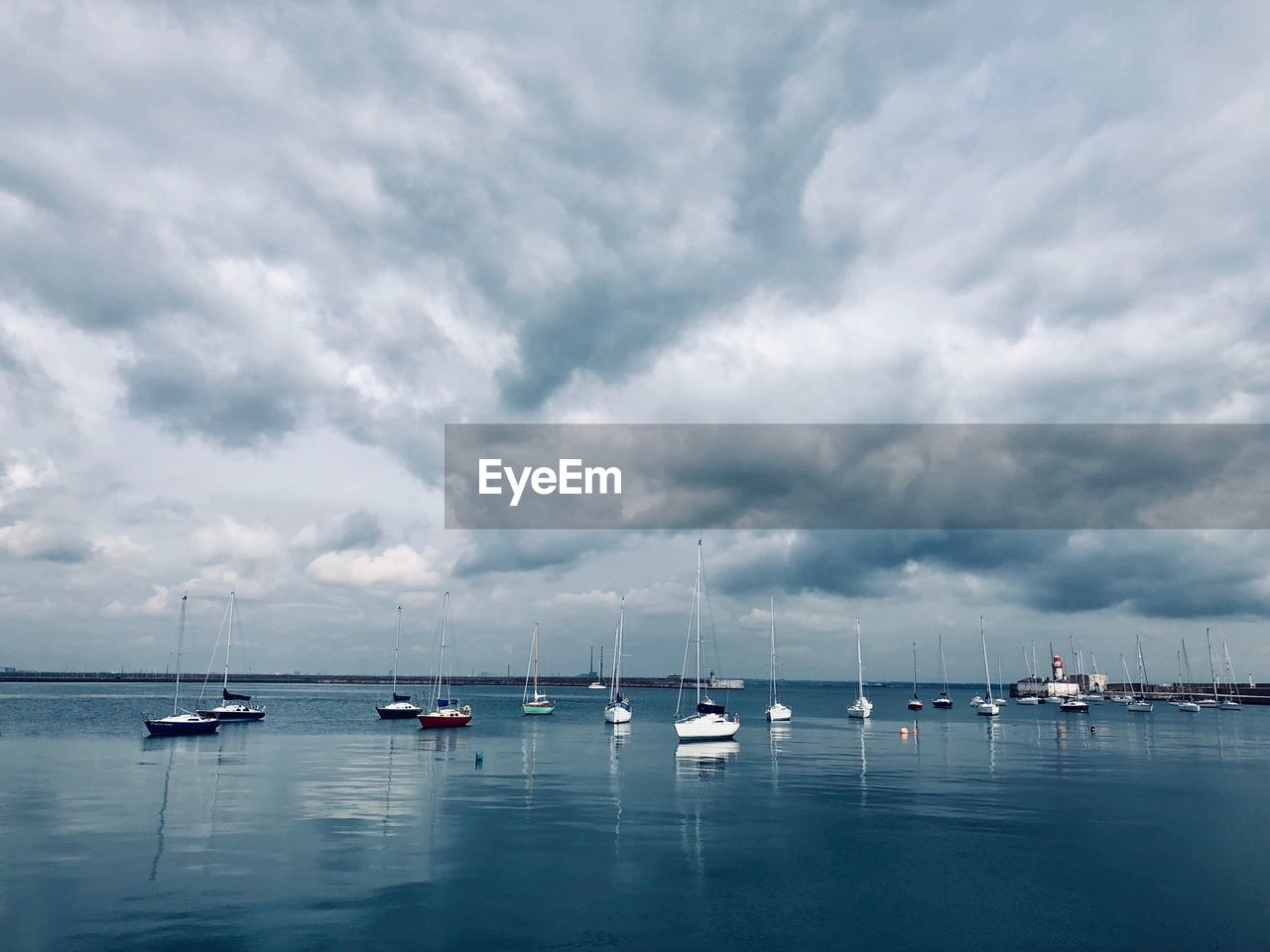 Sailboats moored in sea against sky