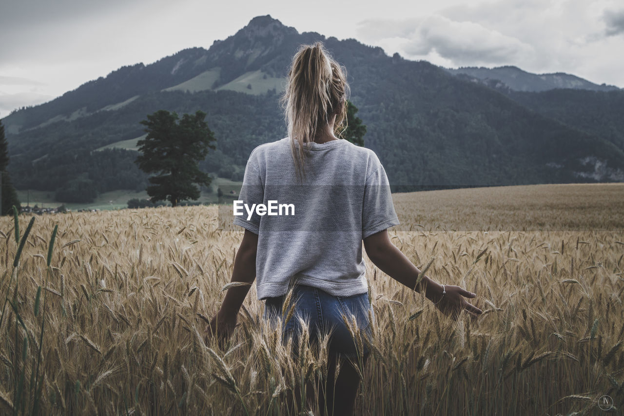 Rear view of woman standing in wheat field