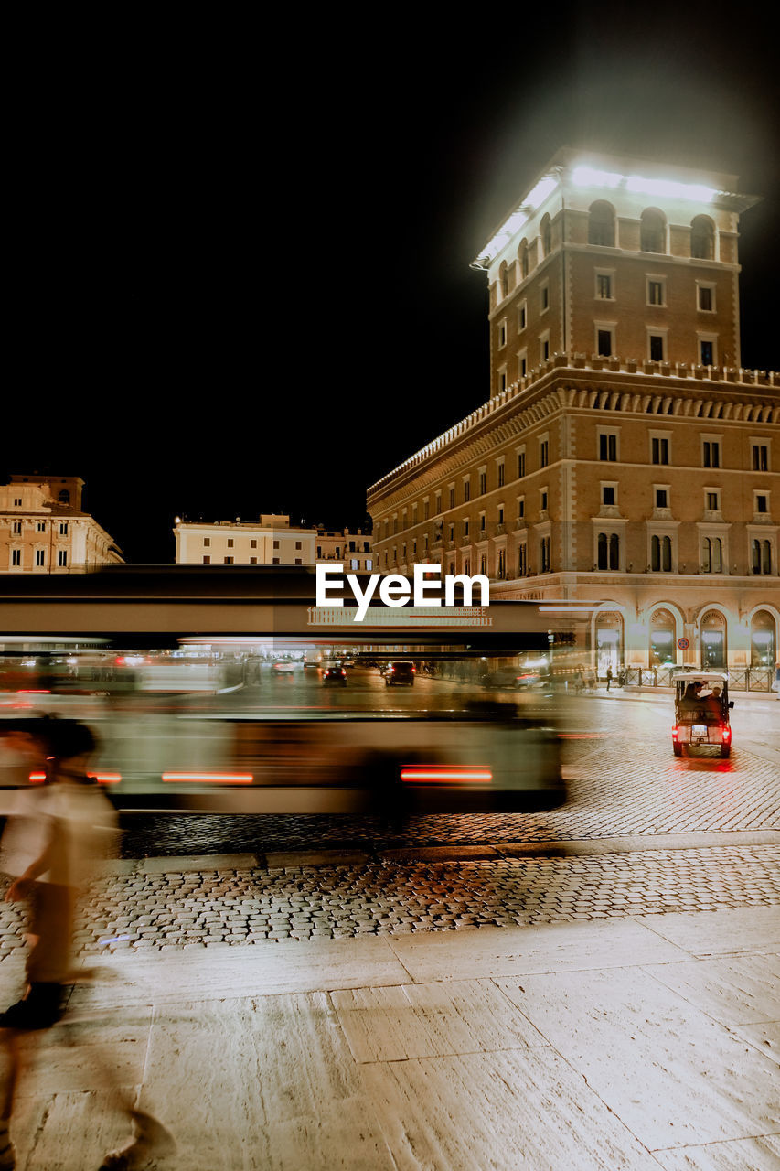 architecture, night, city, built structure, building exterior, blurred motion, illuminated, motion, transportation, mode of transportation, street, light, long exposure, speed, travel destinations, car, city life, travel, motor vehicle, cityscape, evening, on the move, lighting, reflection, outdoors, road, building, city street, land vehicle, nature, sky, public transportation, light trail