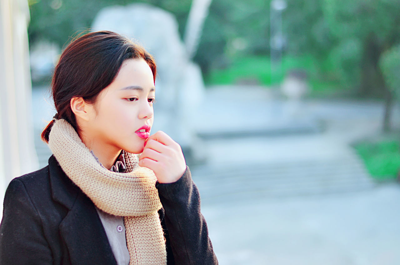 Thoughtful young woman wearing warm clothing at park