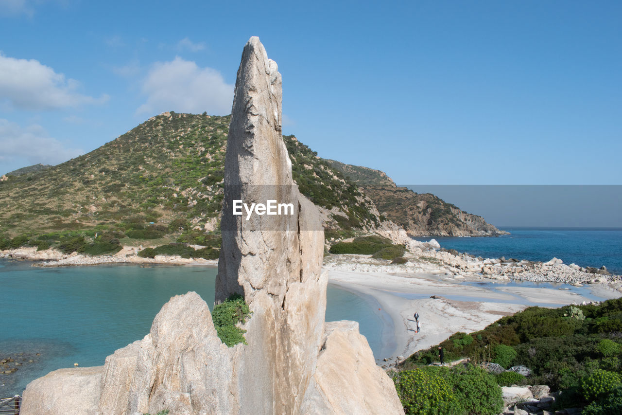 Scenic view of rocky beach against blue sky