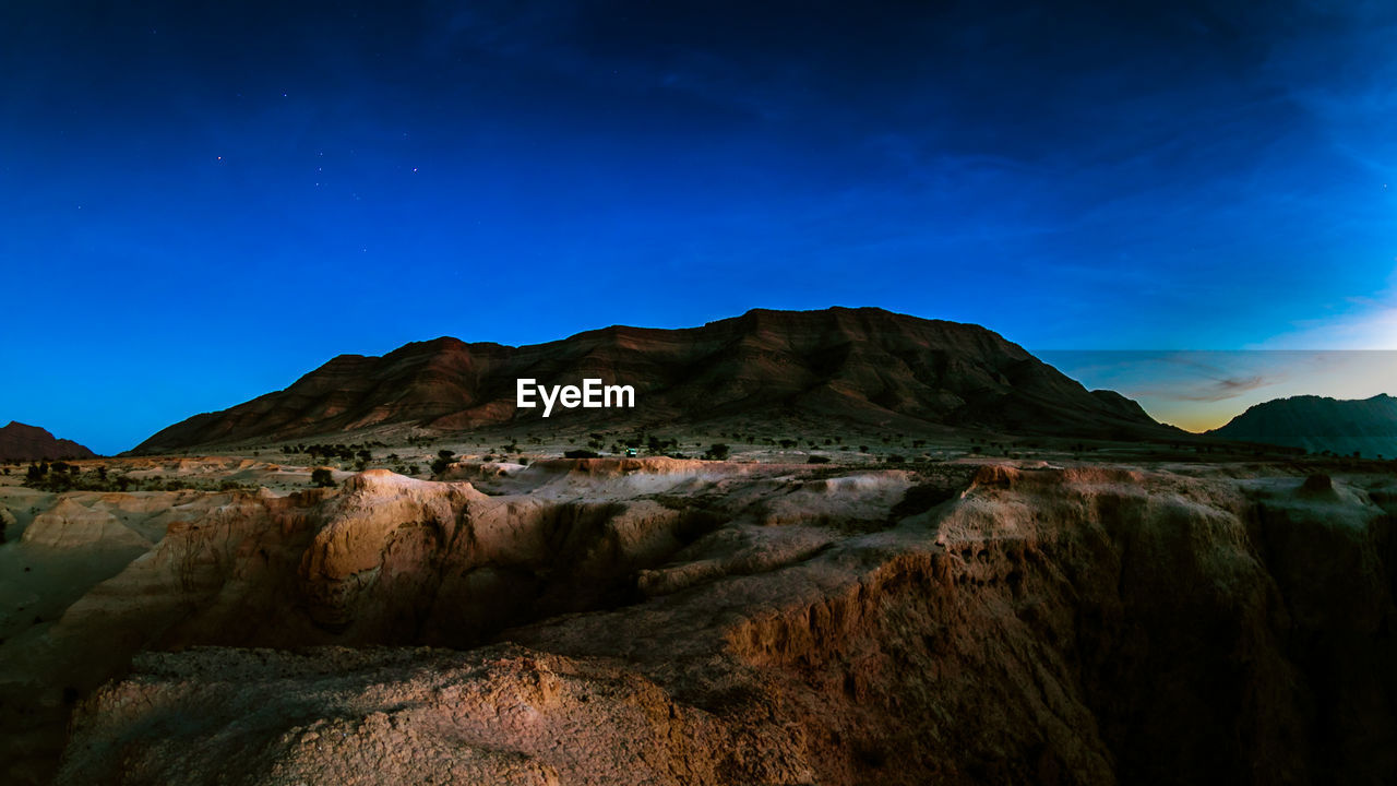 Scenic view of mountains against blue sky at dusk