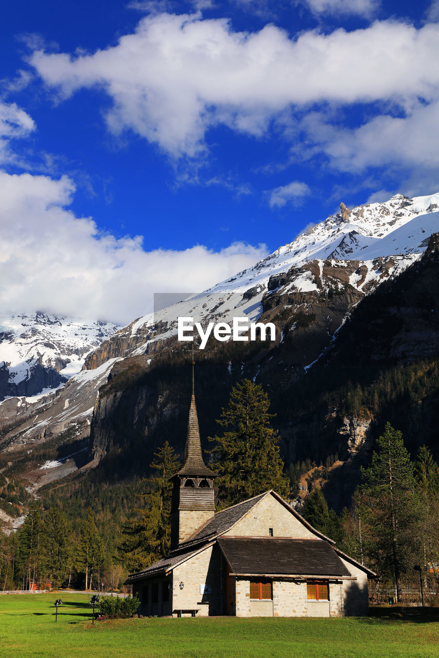 Church on field against snowy mountains