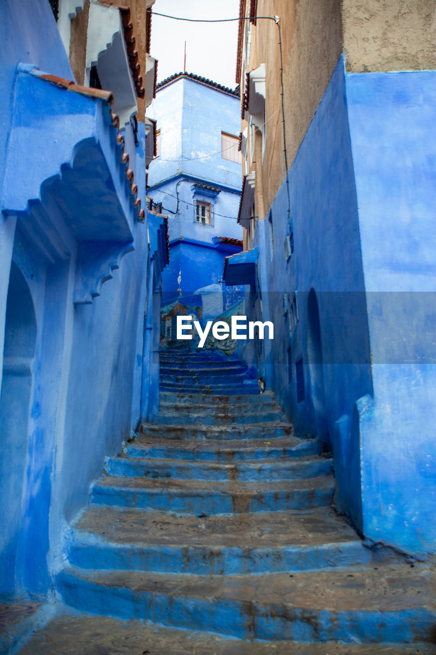 LOW ANGLE VIEW OF STAIRCASE AMIDST BUILDINGS