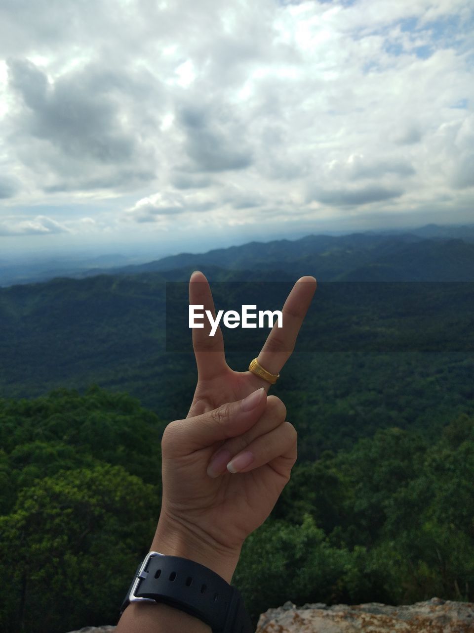 MIDSECTION OF PERSON WITH HAND AGAINST CLOUDY SKY