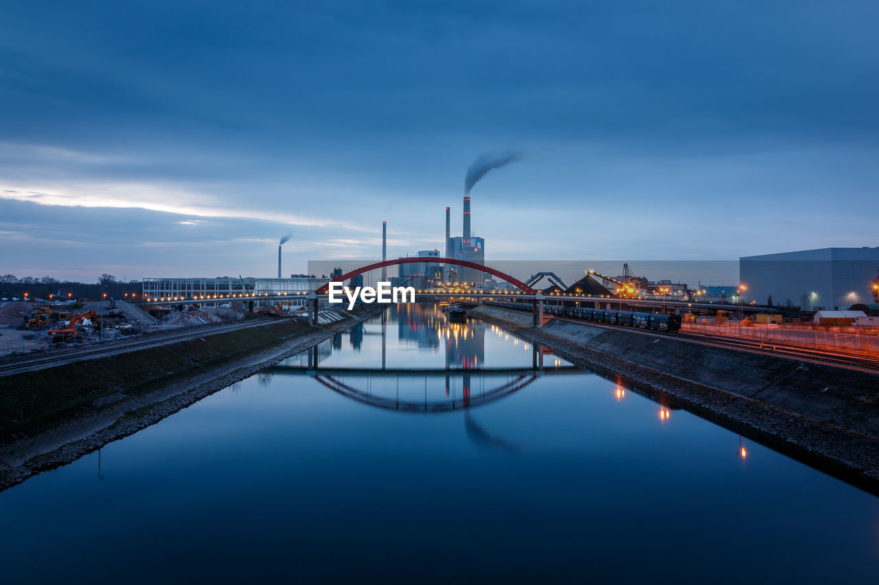 Illuminated bridge over river against sky in city