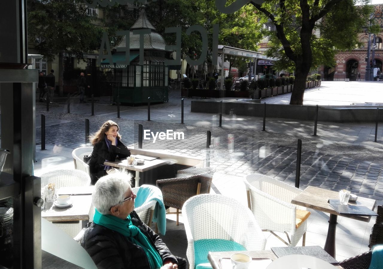 REAR VIEW OF PEOPLE SITTING IN PARK