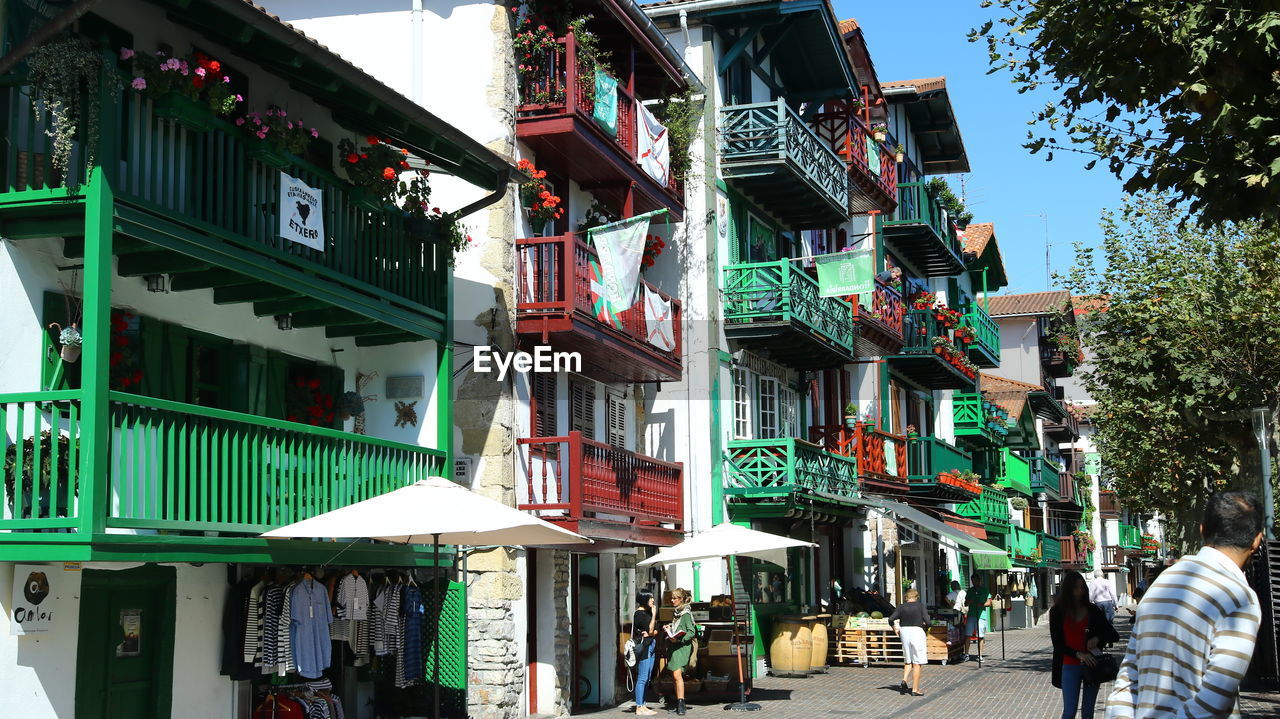 PEOPLE WALKING ON STREET AMIDST BUILDINGS