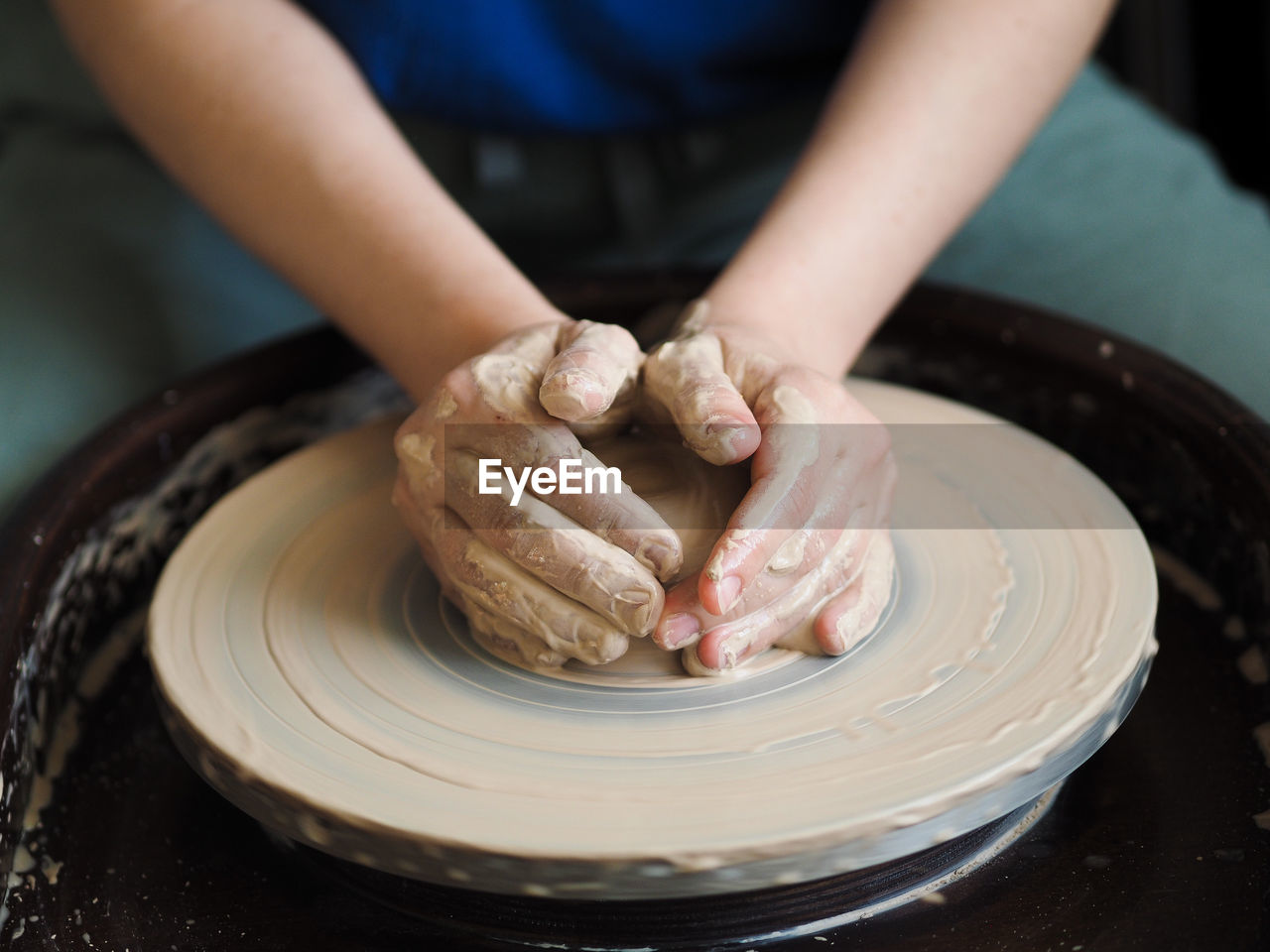 Midsection of woman making earthenware at workshop