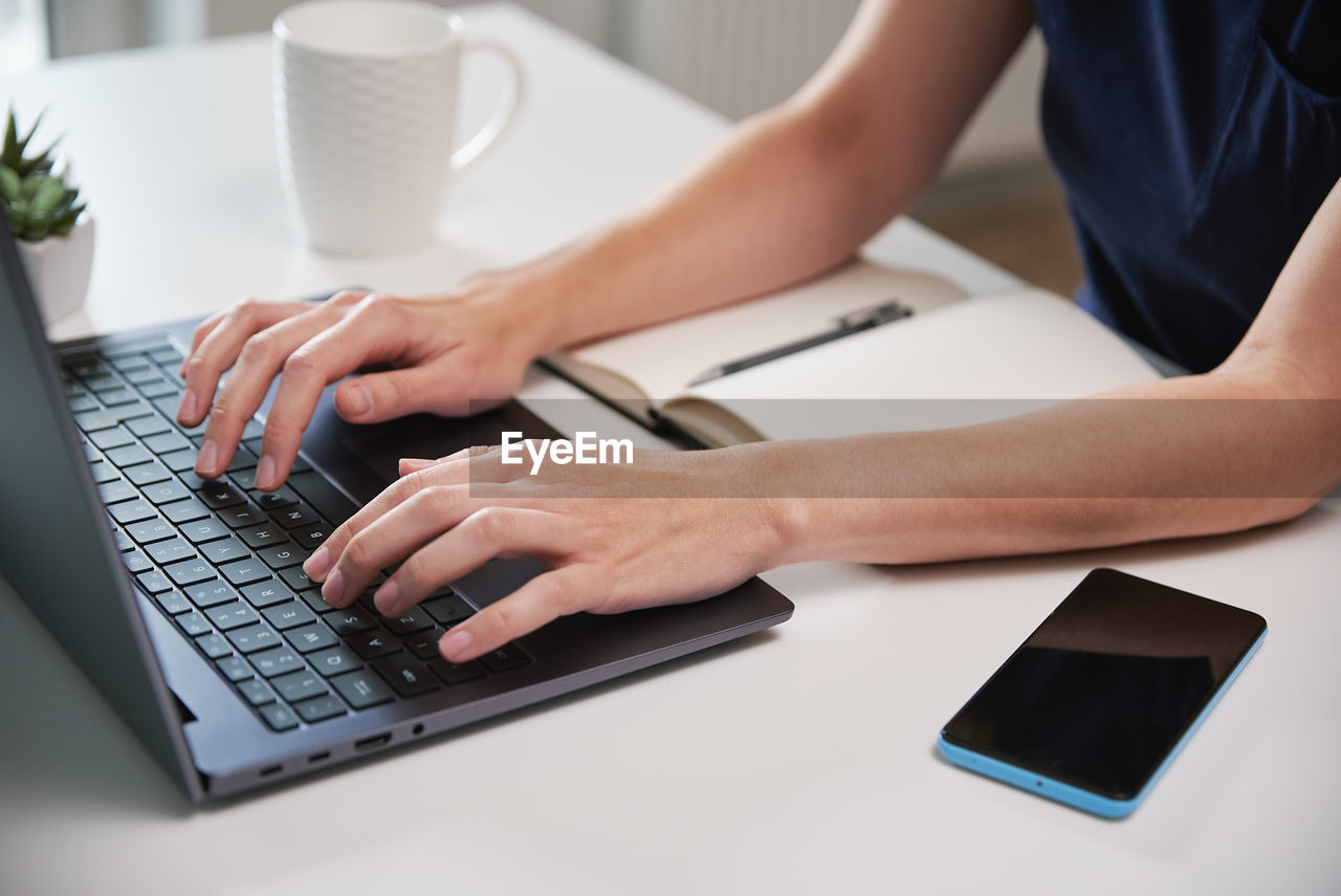 Woman working remotely from home office, using laptop