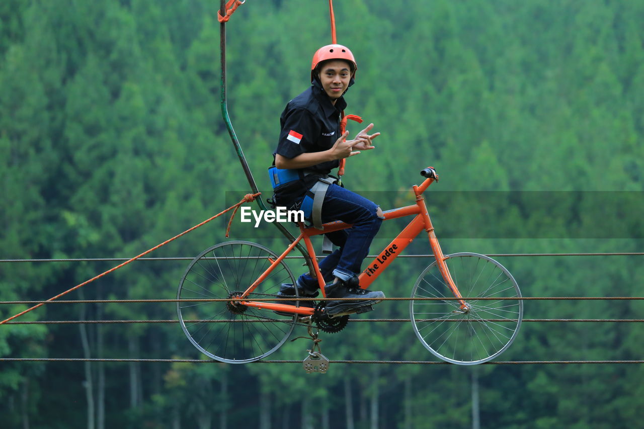 FULL LENGTH OF MAN RIDING BICYCLE ON CHAIN