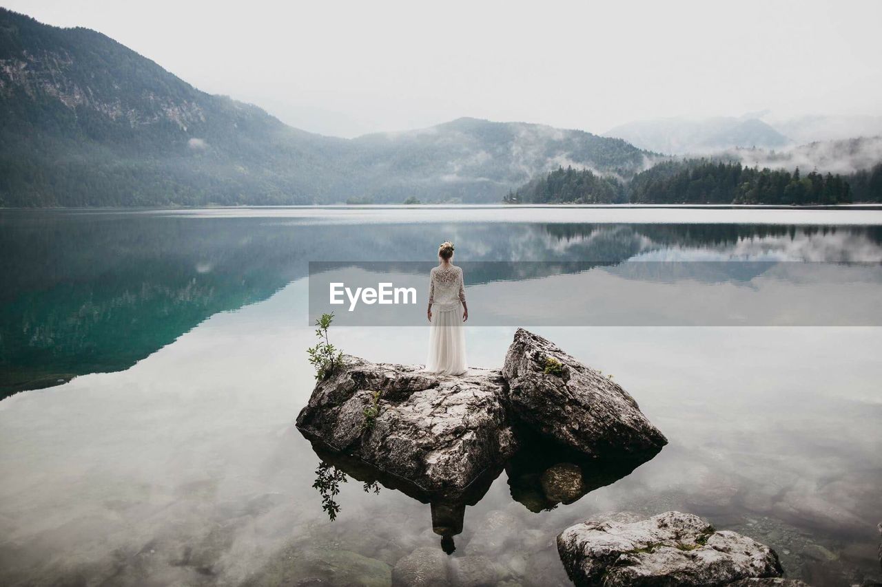 Woman in lake against mountains