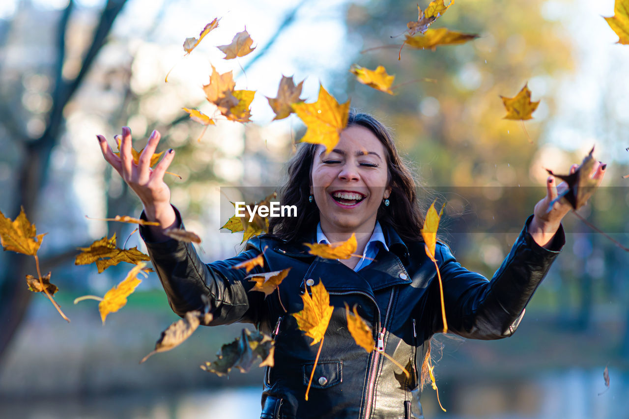 Woman standing while throwing leaves during autumn