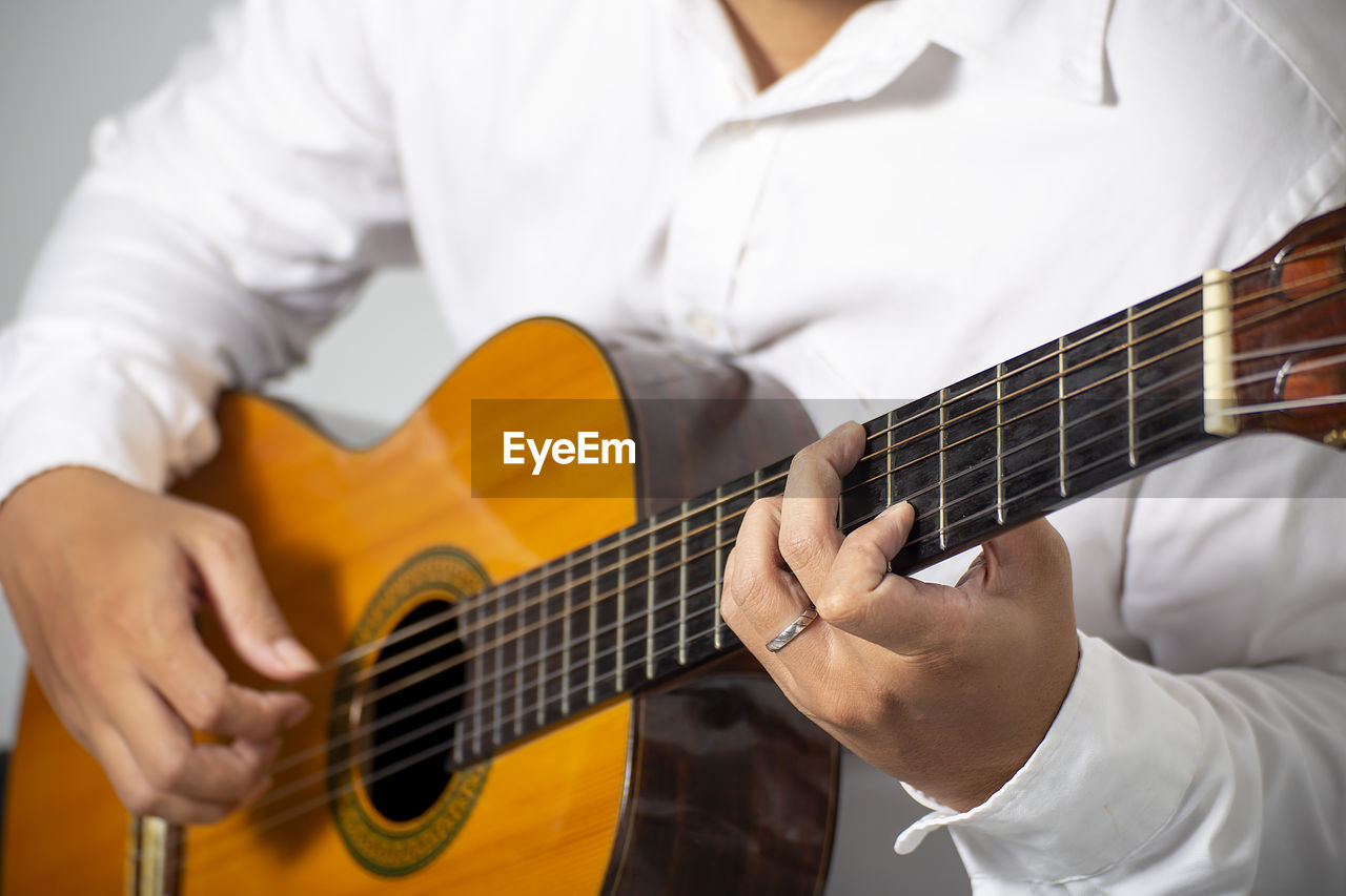 Midsection of man playing guitar