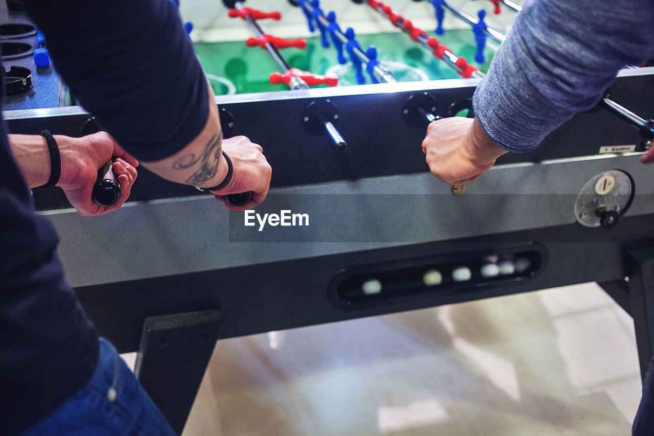 Midsection of friends playing foosball