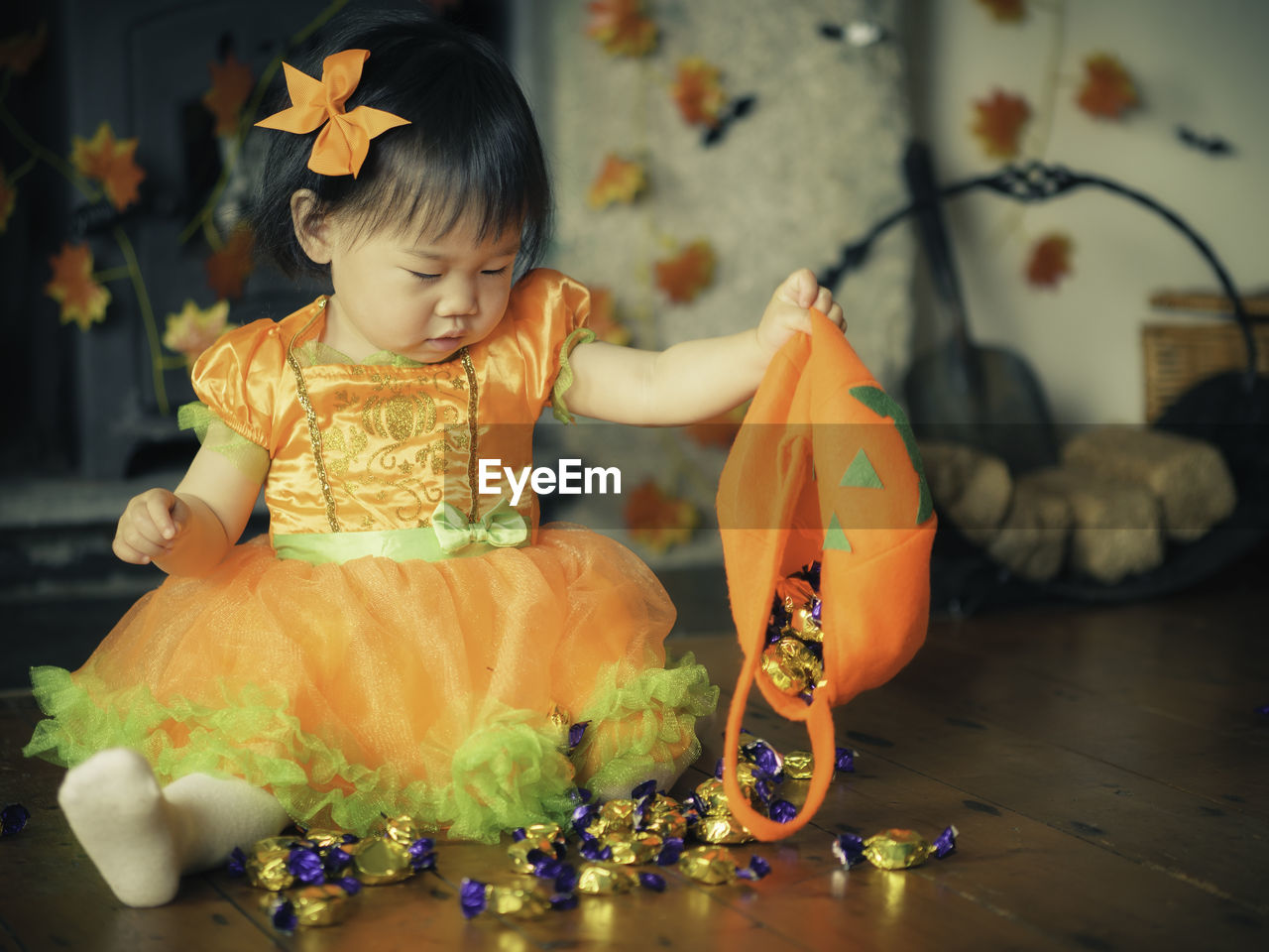 Baby girl holding jack o lantern basket with candies at home