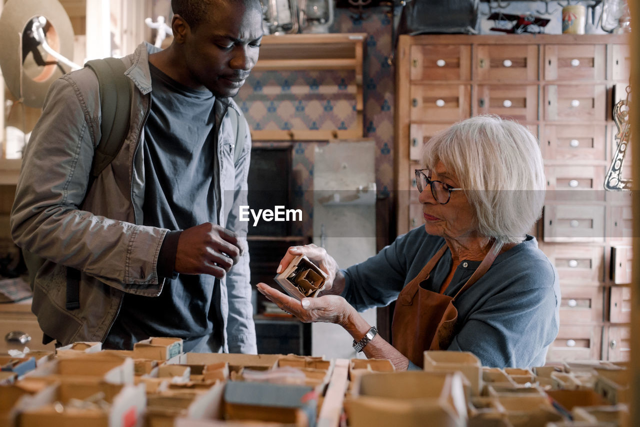 Senior saleswoman assisting male customer with nails at hardware store