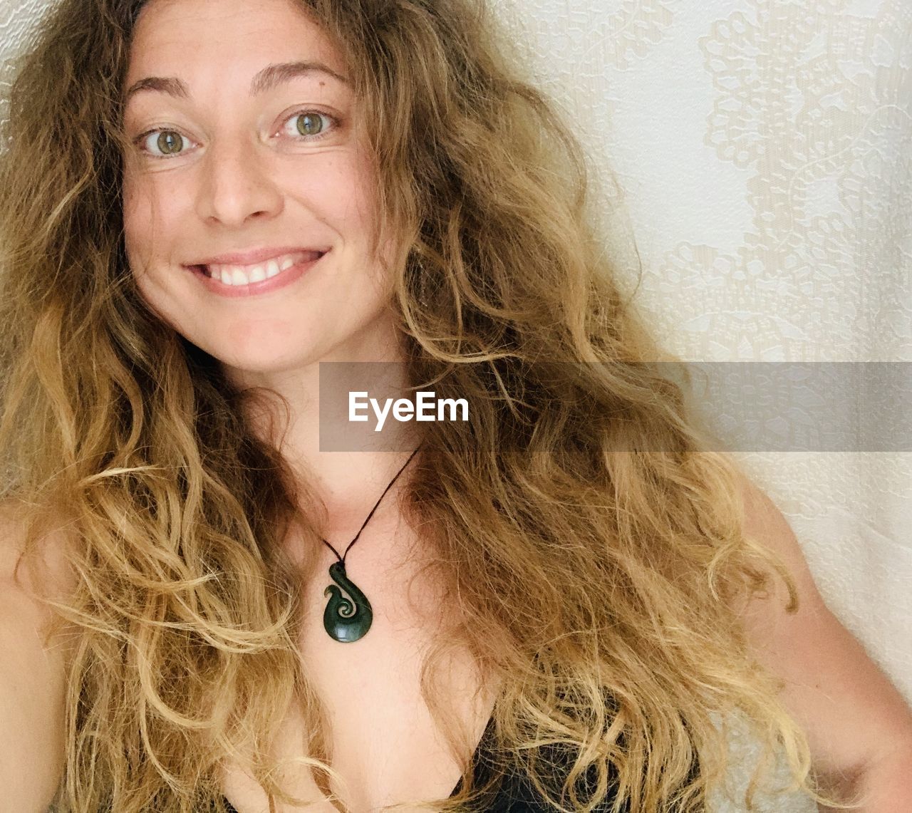 Portrait of smiling woman against wall