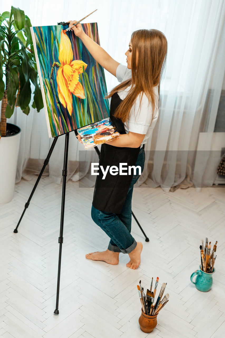 SIDE VIEW OF WOMAN STANDING ON TABLE