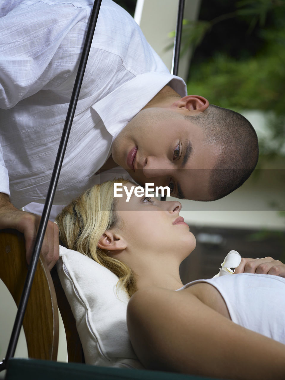 Close-up of boyfriend kissing girlfriend lying on swing