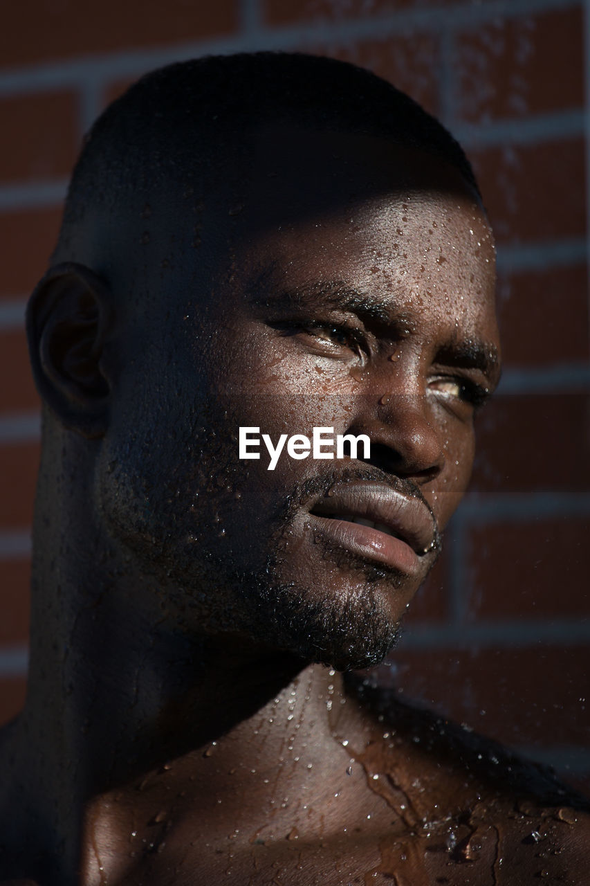 Close-up of man with wet face against wall