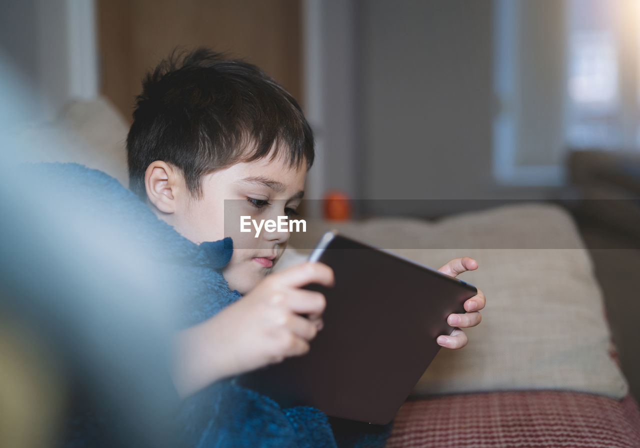 side view of young woman using digital tablet at home