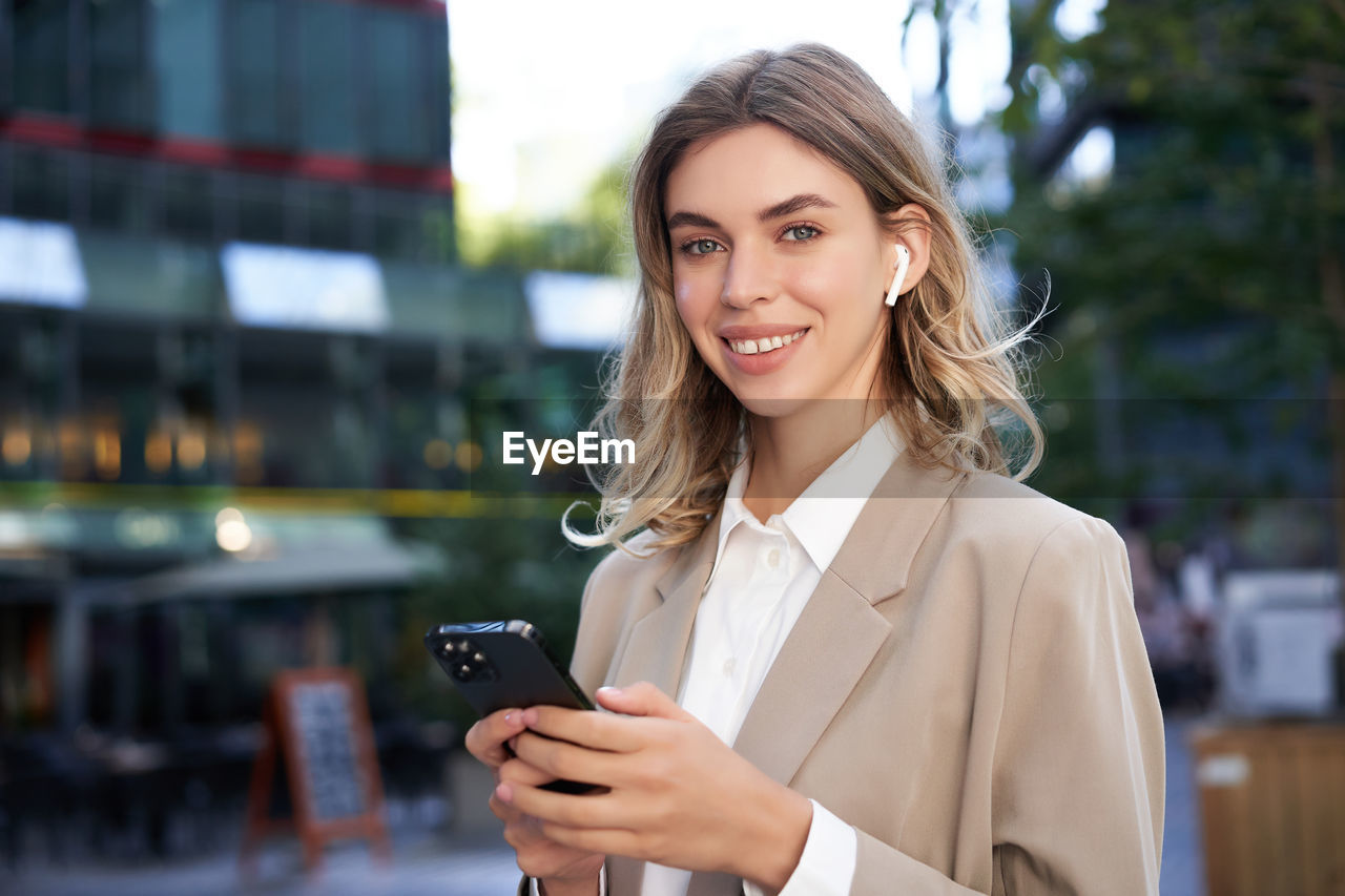 portrait of young businesswoman using mobile phone in city