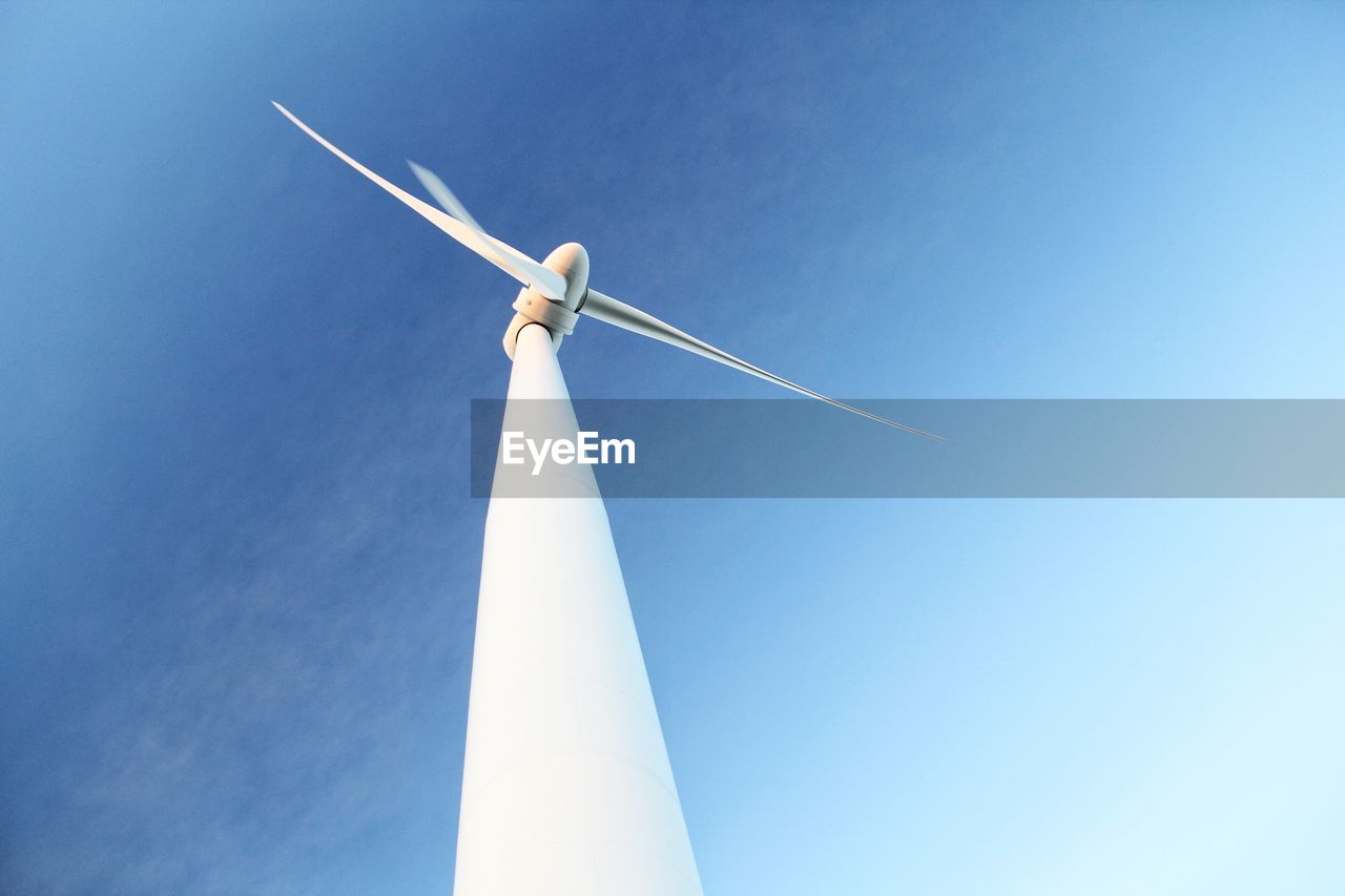 Low angle view of wind turbine against blue sky