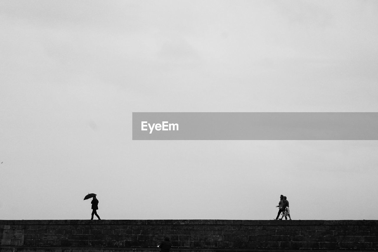 Silhouette people riding bicycle on field against sky