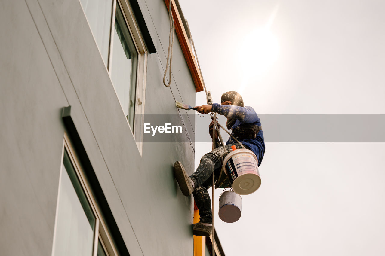 LOW ANGLE VIEW OF MAN WORKING AT CONSTRUCTION SITE