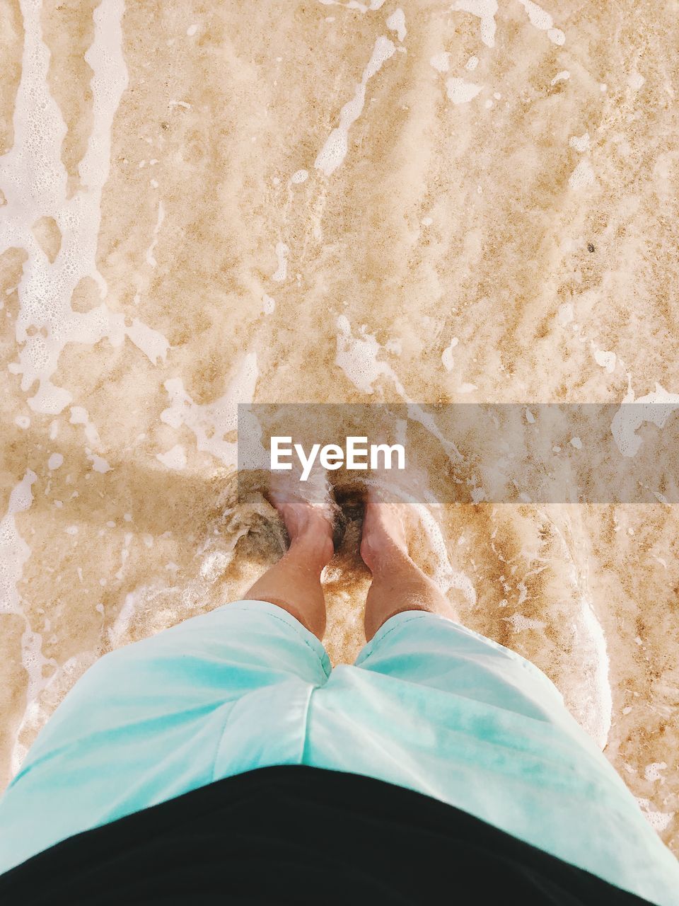 Low section of woman standing at beach