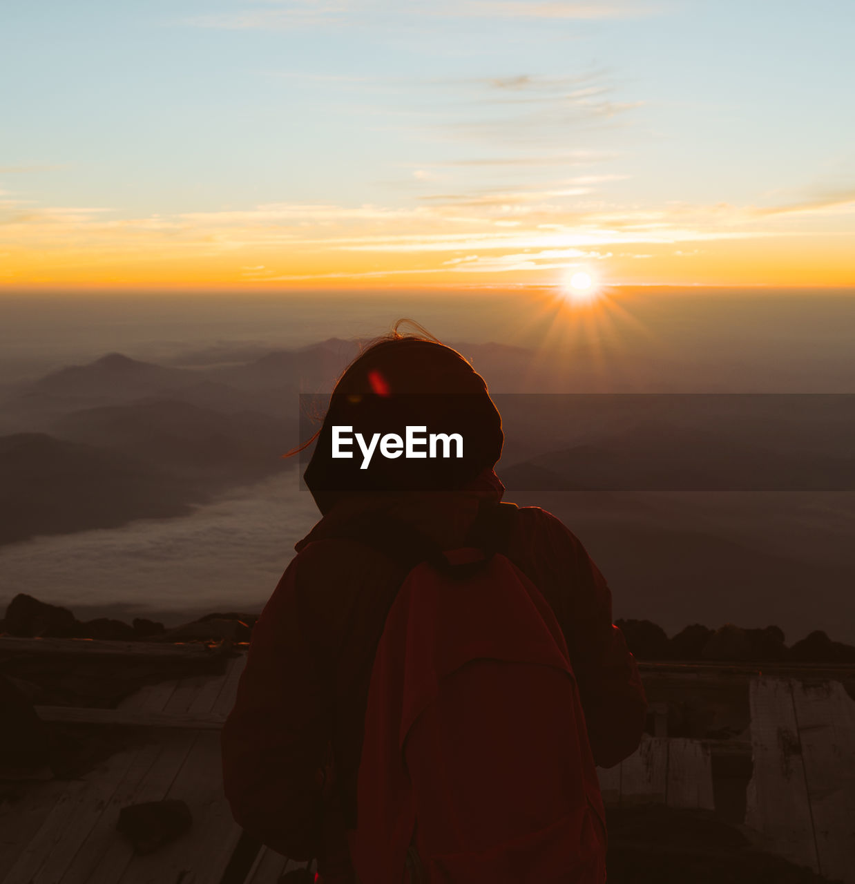 Rear view of woman standing against sky during sunrise