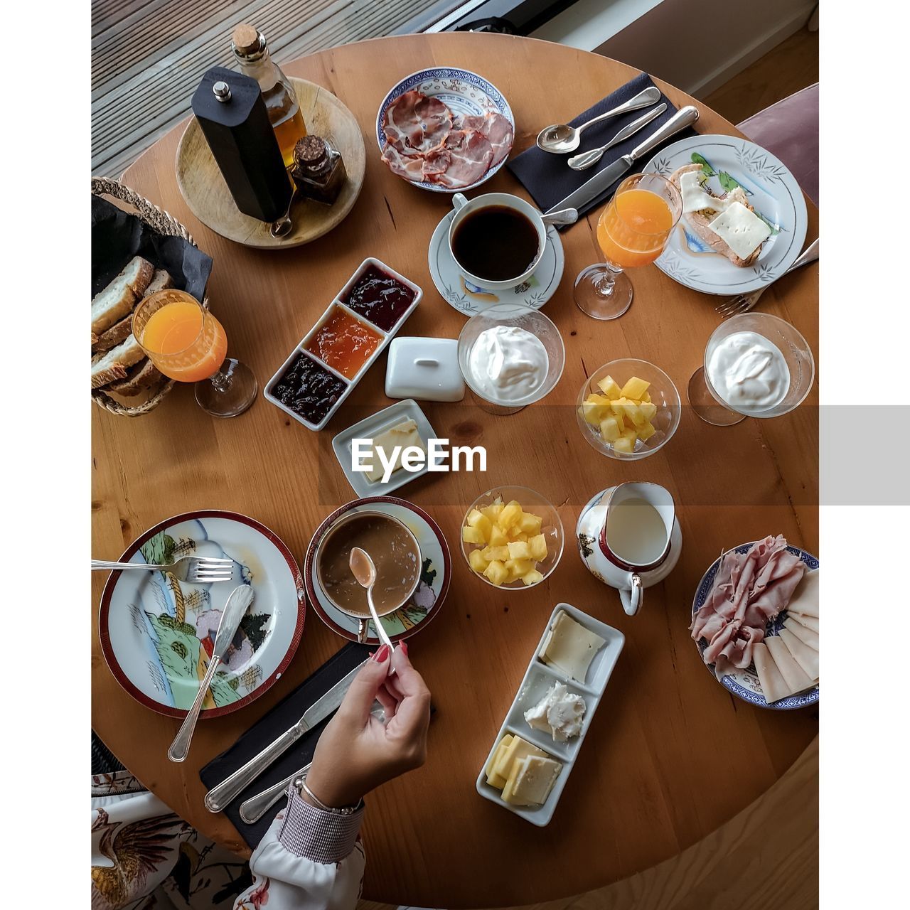 High angle view of cropped hand of woman having breakfast on table