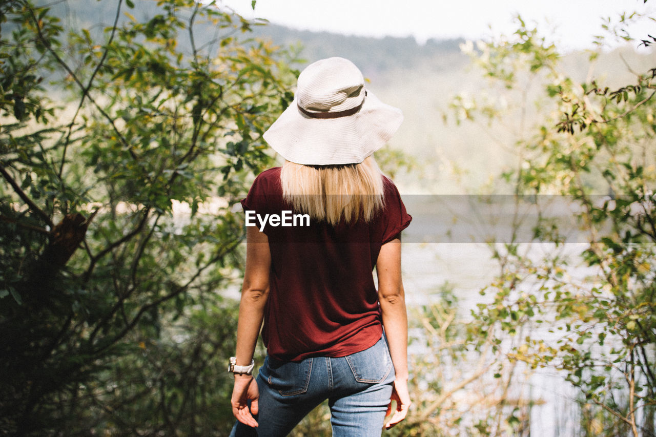 Rear view of woman standing by trees